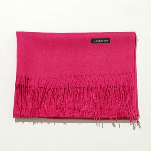Detail shot of a rose red cashmere scarf showing soft fabric texture and fringe tassels