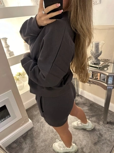 Women's athletic two-piece set with a loose dark grey hoodie and matching gym shorts