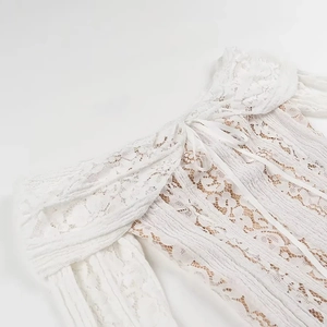 Detailed close-up of white off-the-shoulder lace dress showing floral patterns and texture