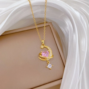Detail of gold crescent moon and planet pendant with pink heart stone and crystals