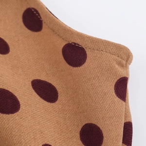 Detailed macro shot of mustard yellow midi dress fabric with burgundy polka dot pattern