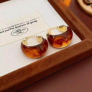 Detailed macro view of vintage gold-plated hoop earrings with amber resin texture