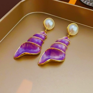 Detail of vintage gold seashell earrings with purple enamel and white pearl accents