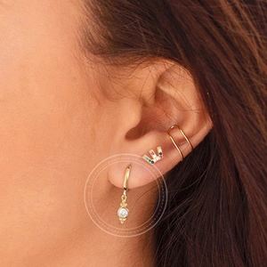 Luxury gold drop earrings with round clear zircon stones worn by a model in a close-up view