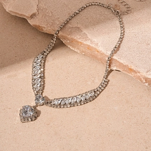 Detail shot of a silver heart pendant necklace with cubic zirconia on a stone surface