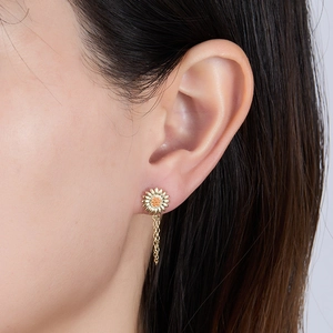 Close-up view of an elegant gold sunflower stud earring with tassel chain on a model's ear