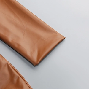 Vue détaillée de la texture en similicuir marron et des coutures d'une robe ajustée