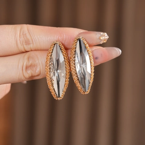 Macro shot of marquise-cut crystal earrings with gold beaded edges held by hand