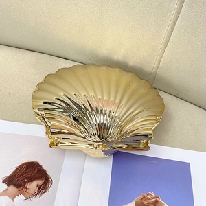 Top view of a gold shell-shaped clutch with amber texture on a lifestyle background