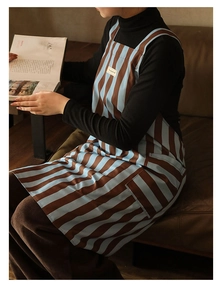 Detail of kitchen apron with blue and brown stripes featuring a front pocket and logo label