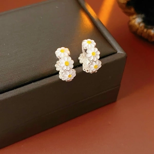 Detailed shot of vintage white daisy enamel hoop earrings on a premium black gift box