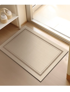Close-up of rectangular beige diatom mud bath mat with brown border on wooden floor