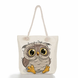 Close-up of the beige canvas tote bag featuring a cute cartoon owl print and rope handles