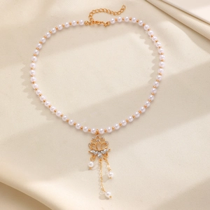 Close-up detail of vintage beaded choker necklace with pearl beads and gold floral pendant.