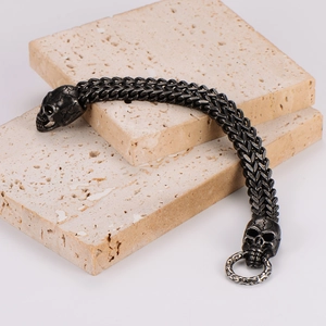 Dettaglio del bracciale a catena punk con teschio su pietra beige e trama in metallo