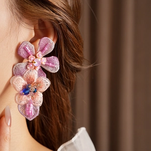 Detailed view of handmade pink knit flower earrings with colorful center beads on a model