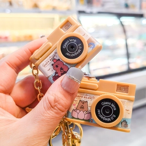Close-up of retro camera keychains with cute capybara illustrations and gold metal chains