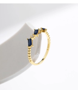 Close-up of S925 hallmark on a gold geometric ring with blue gems and diamonds