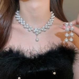 Detail shot of elegant floral pearl necklace and long earrings set on model