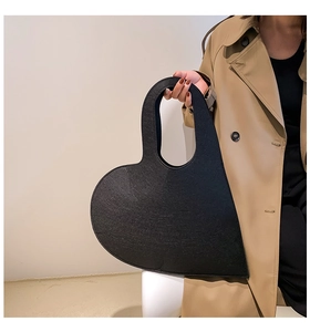 Fashionable black heart-shaped felt handbag held by a model in a minimalist setting