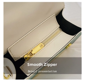 Detail shot of smooth gold zipper and white faux leather texture of the handbag
