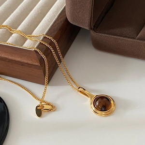 Elegant gold necklace with oval smoky quartz pendant on wooden display stand