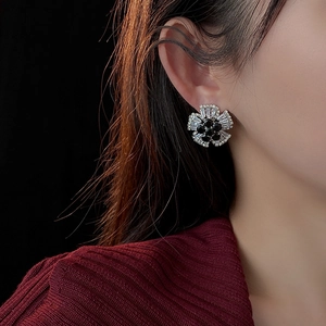 Detailed view of flower-shaped stud earrings with black stones and sparkling zircons