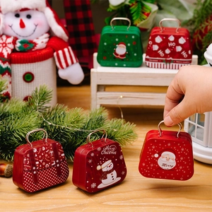 Detailed view of mini Christmas tin suitcase boxes with festive illustrations on wood