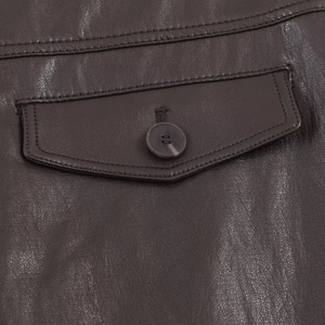 Vue macro détaillée de la poche d'une jupe en cuir marron foncé avec bouton assorti