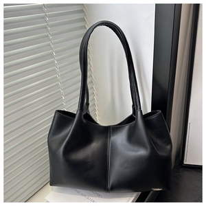 Detail of minimalist black leather tote bag with vertical stitching on stacked books