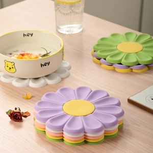 Daisy shaped silicone heat resistant coasters in various colors on wooden table