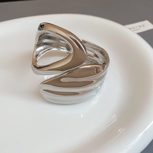 Macro shot of silver irregular geometric ring on white porcelain tray with metallic texture