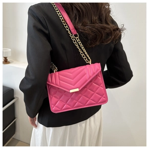 Detailed view of the rose red quilted leather bag with a gold chain strap on a model