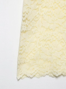 Close-up of intricate light yellow floral lace fabric with delicate scalloped edges