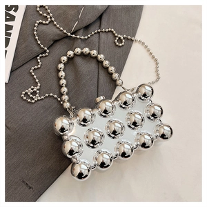 Detail of silver metallic sphere bag with polished spherical texture and pearl bead chain