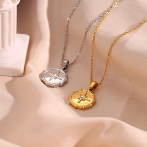 Macro shot of gold and silver compass pendants with white zircon on silk fabric