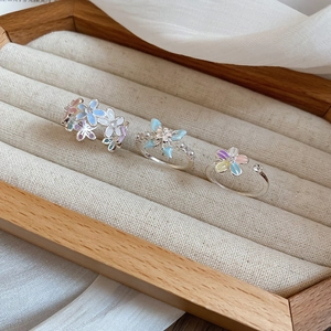 Détails de bagues fleurs et papillons pastel présentées sur un plateau à bijoux