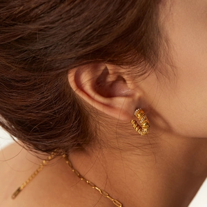 Close-up of vintage C-shape gold earrings with texture and sparkling zircon stones