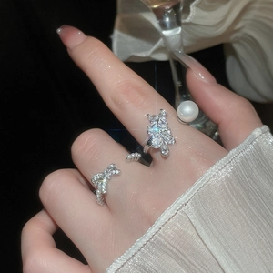 Macro detail of luxury bow and floral cluster rings with zircon stones and pearls
