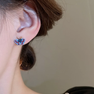 Detailed close-up of butterfly stud earring featuring blue enamel and red rhinestones