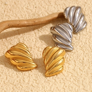 Macro shot of 18K gold and silver plated stainless steel earrings with textured wing patterns