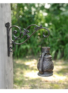 Detail einer Wandhalterung aus Gusseisen mit hängender antiker Bronze-Laterne für Gärten