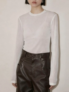Detail of white bamboo texture knit top paired with dark brown faux leather trousers