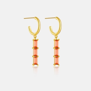 Detail view of gold long earrings with triple stacked orange rectangular zircon stones