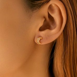 Close-up of elegant 18K gold crescent moon stud earrings with pavé set cubic zirconia