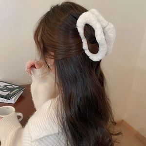 Detailed back view of a white plush faux fur shark hair clip worn in a minimalist hairstyle