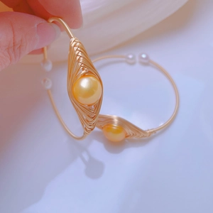 Dettaglio macro del bracciale avvolto in filo d'oro con perle dorate e bianche