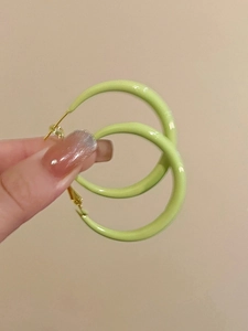 Close-up of bright green C-shaped hoop earrings with a smooth polished enamel finish