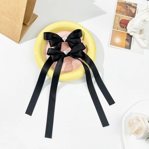 Detailed view of black satin bow hair clips with central heart-shaped crystal rhinestones