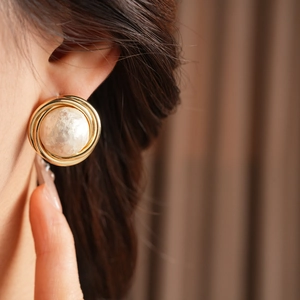 Detailed close-up of retro gold-plated round stud earrings with pearl inlay on a model